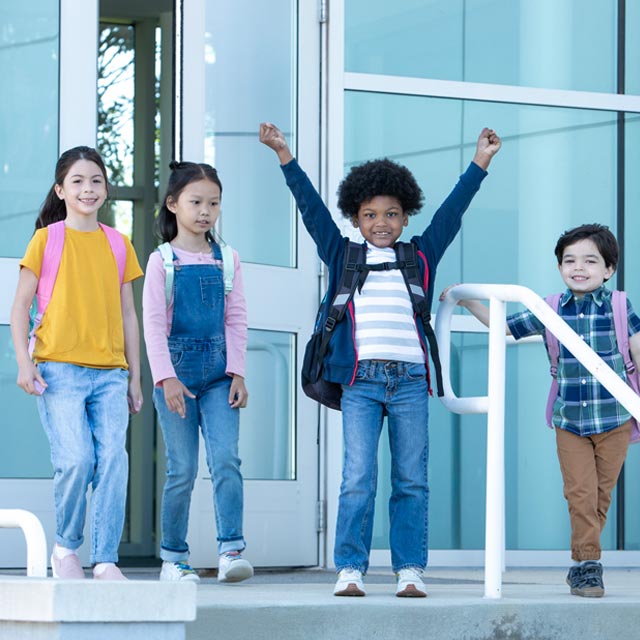 Common Questions- boy celebrates with other kids outside school